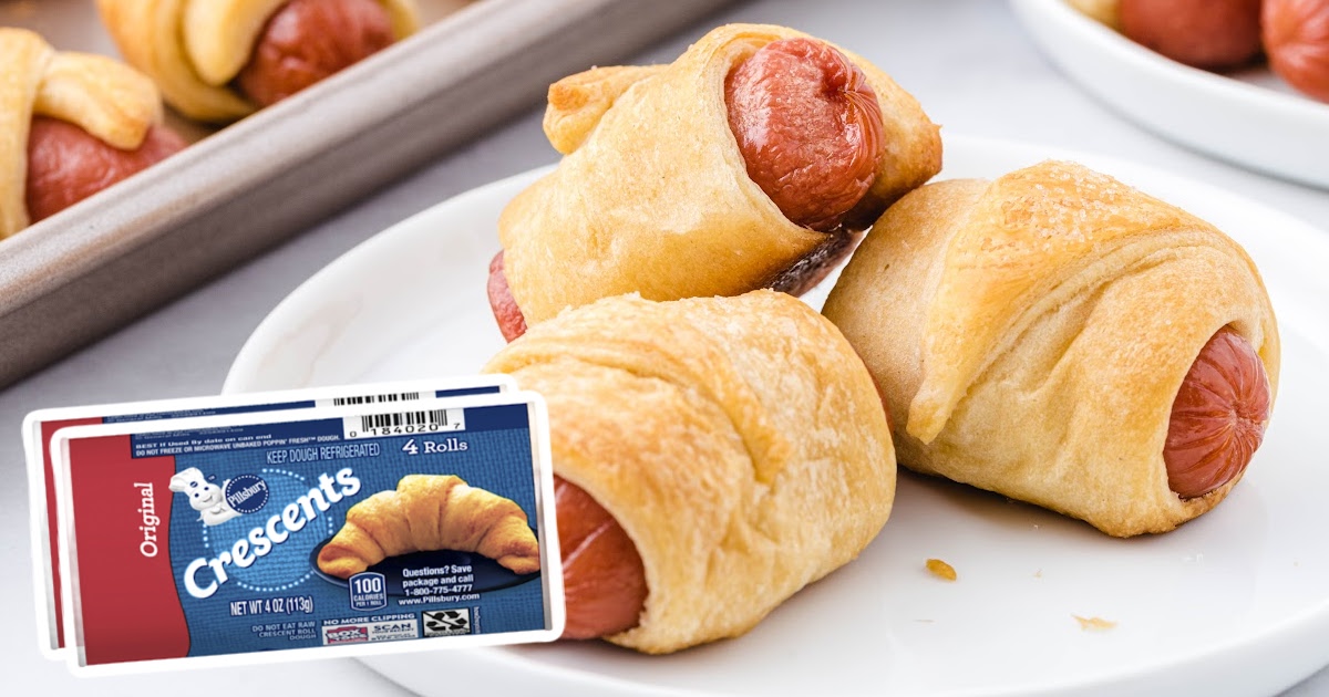 A close-up of several pigs in a blanket served on a white plate, showcasing the fluffy, golden dough and the sausage inside.
