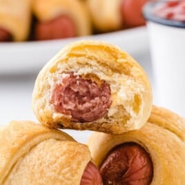 A recipe card featuring instructions for making pigs in a blanket with an image of the snack on the side, perfect for a quick bite.