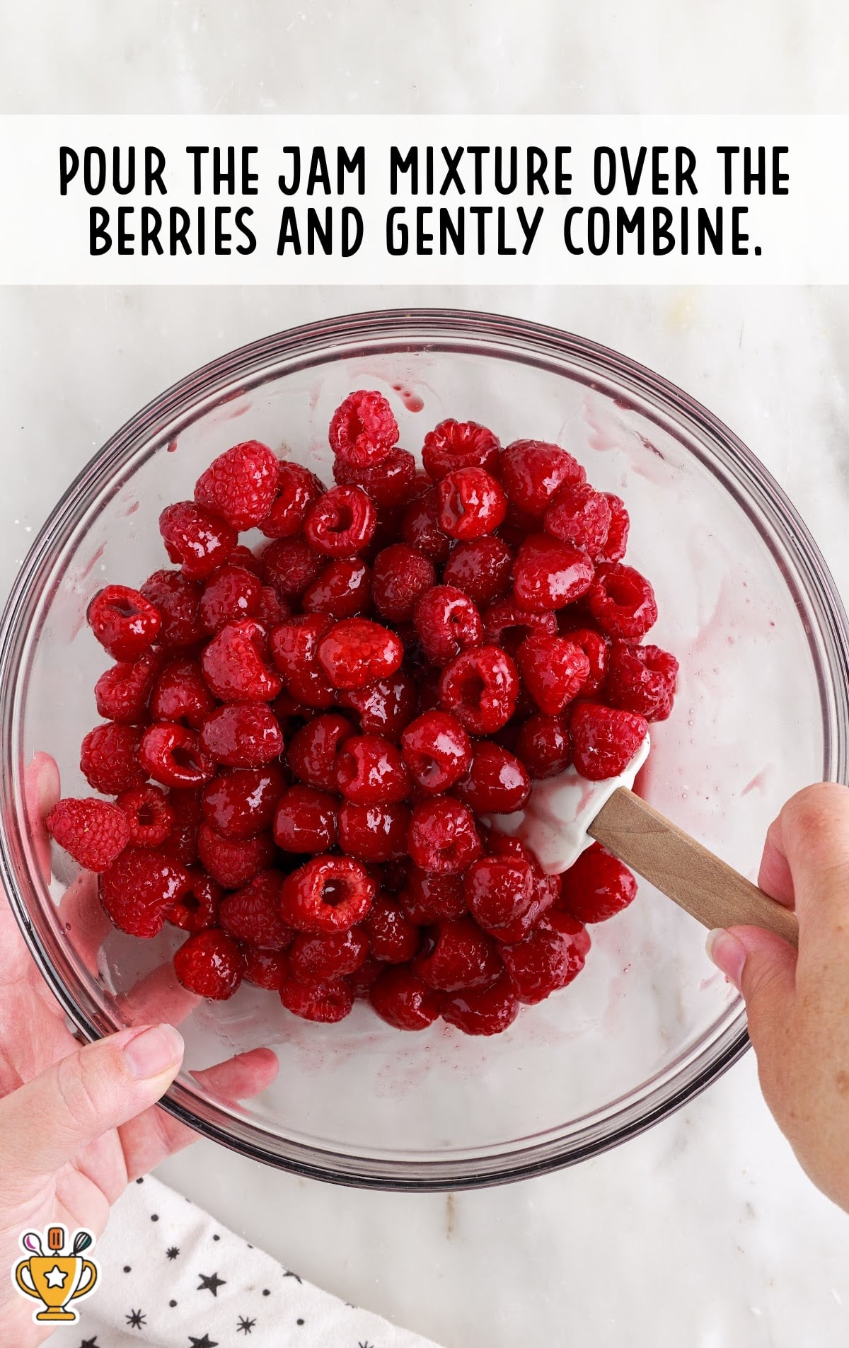 pouring jam mixture over the berries in a bowl