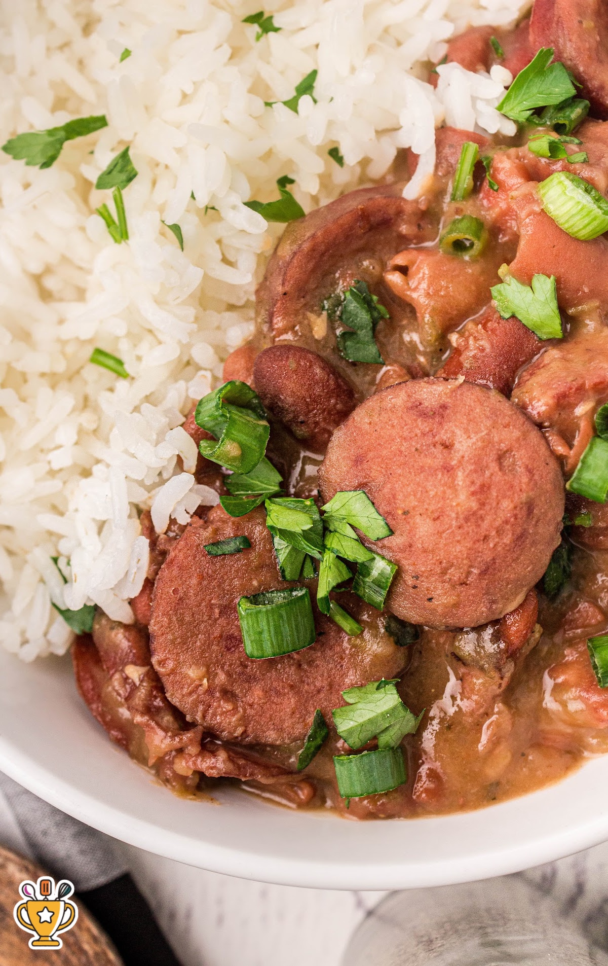 Zoomed-in look at red beans and rice showcasing the creamy texture, sausage slices, and fresh parsley on top.