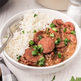 Flat lay of ingredients including sausage, spices, beans, rice, and vegetables labeled for a red beans and rice recipe.