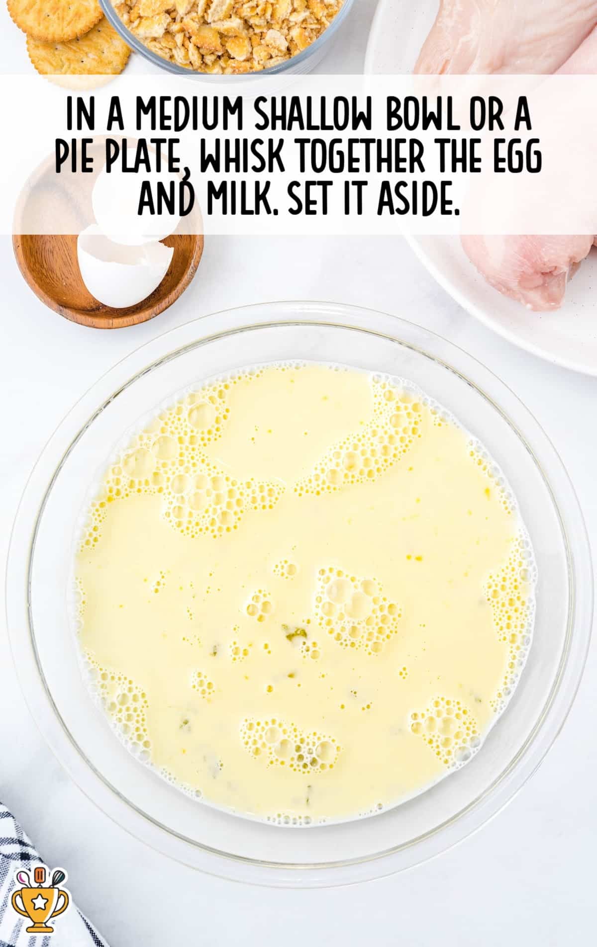 a clear bowl with egg and milk whisked together in it