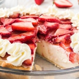 A whole strawberry cream cheese pie with whipped cream borders and sliced strawberries on top.