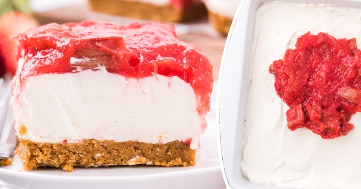 A slice of strawberry rhubarb cheesecake with a topping of red strawberries and rhubarb, sitting perfectly on a graham cracker crust. The cheesecake looks smooth and creamy, ideal for a sweet treat.