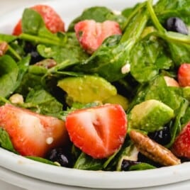 A featured image of a strawberry spinach salad, with vibrant green spinach and red strawberries, perfect for a summer dish, looking fresh and delicious.