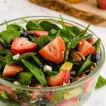 A recipe card with ingredients and preparation steps for a fresh and delicious strawberry spinach salad, with all essential ingredients displayed clearly.