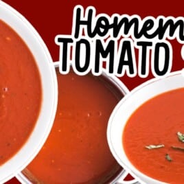 A vibrant shot of creamy homemade tomato soup served in a white bowl, garnished with basil leaves, next to a spoon and crackers.