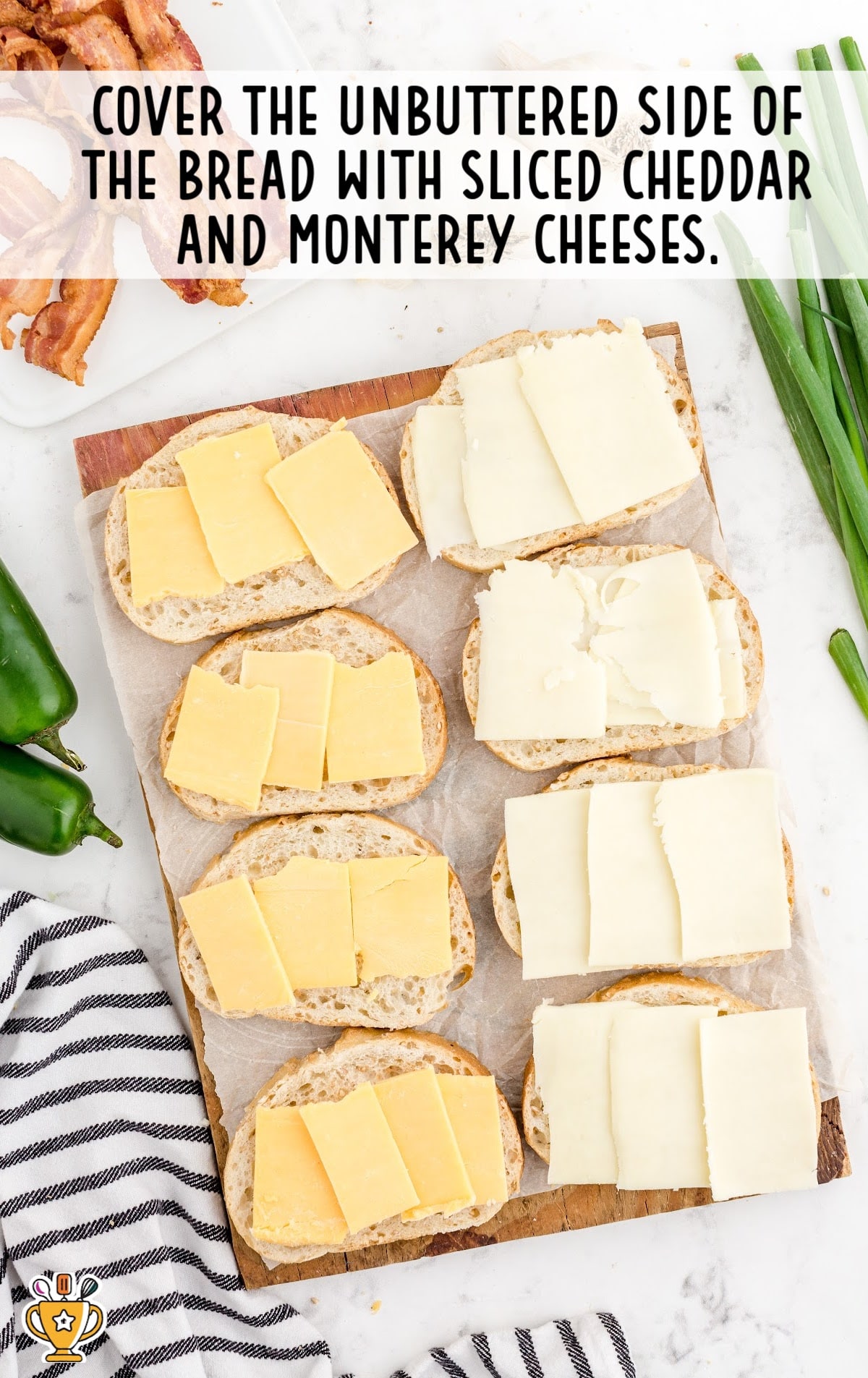 Slices of bread laid out with cheddar and Monterey Jack cheeses on the unbuttered sides, ready to be topped.
