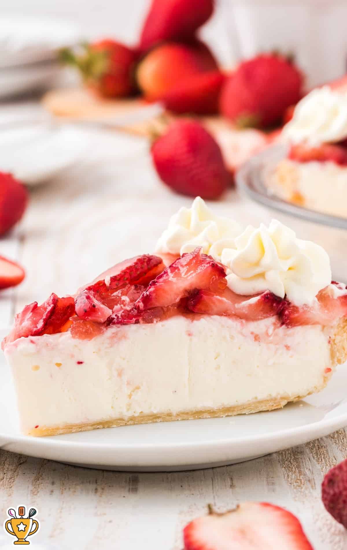 A close-up of a slice of strawberry cream cheese pie showing the creamy filling and fresh strawberries on top.