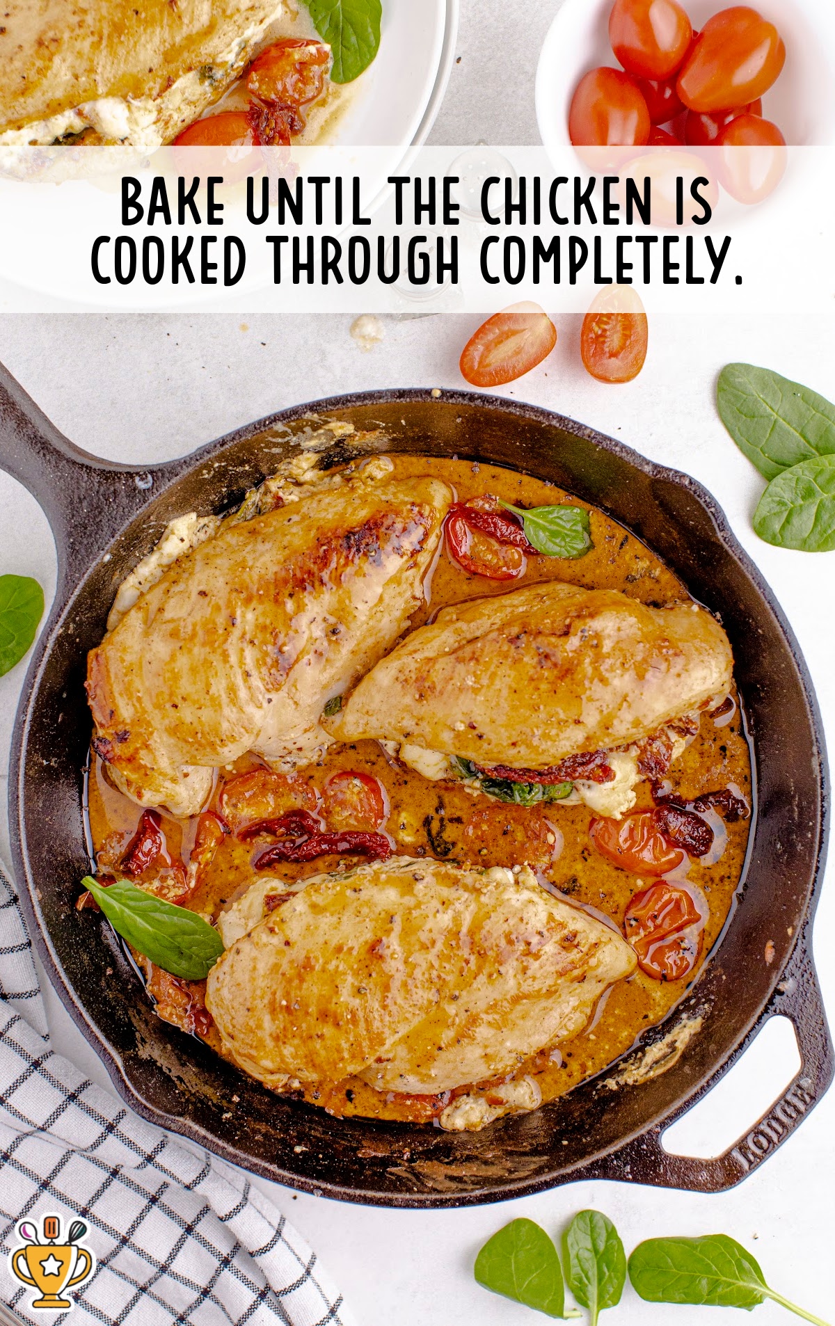 Close-up of the sun-dried tomato stuffed chicken breasts cooking in a skillet with tomatoes and spinach surrounding them.