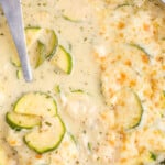 Creamy zucchini gratin in a skillet topped with melted golden cheese, with zucchini slices visible in the sauce. Text overlay reads “Zucchini gratin recipe – made in one skillet!