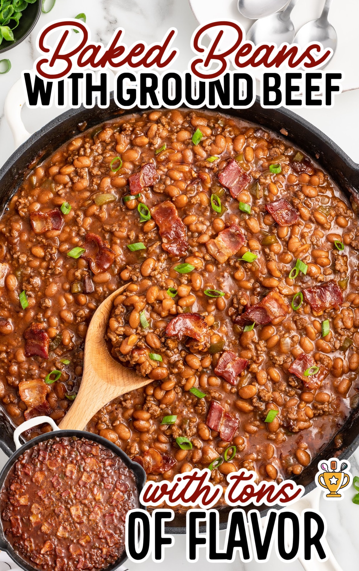 Overhead view of baked beans with ground beef in a cast iron skillet, topped with crispy bacon and green onions, with a wooden spoon scooping a portion; text overlay reads &ldquo;Baked Beans with Ground Beef with tons of flavor.&rdquo;