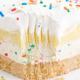 Birthday cake delight bars served on a white plate, ready to eat with festive sprinkle topping and smooth pudding layers.