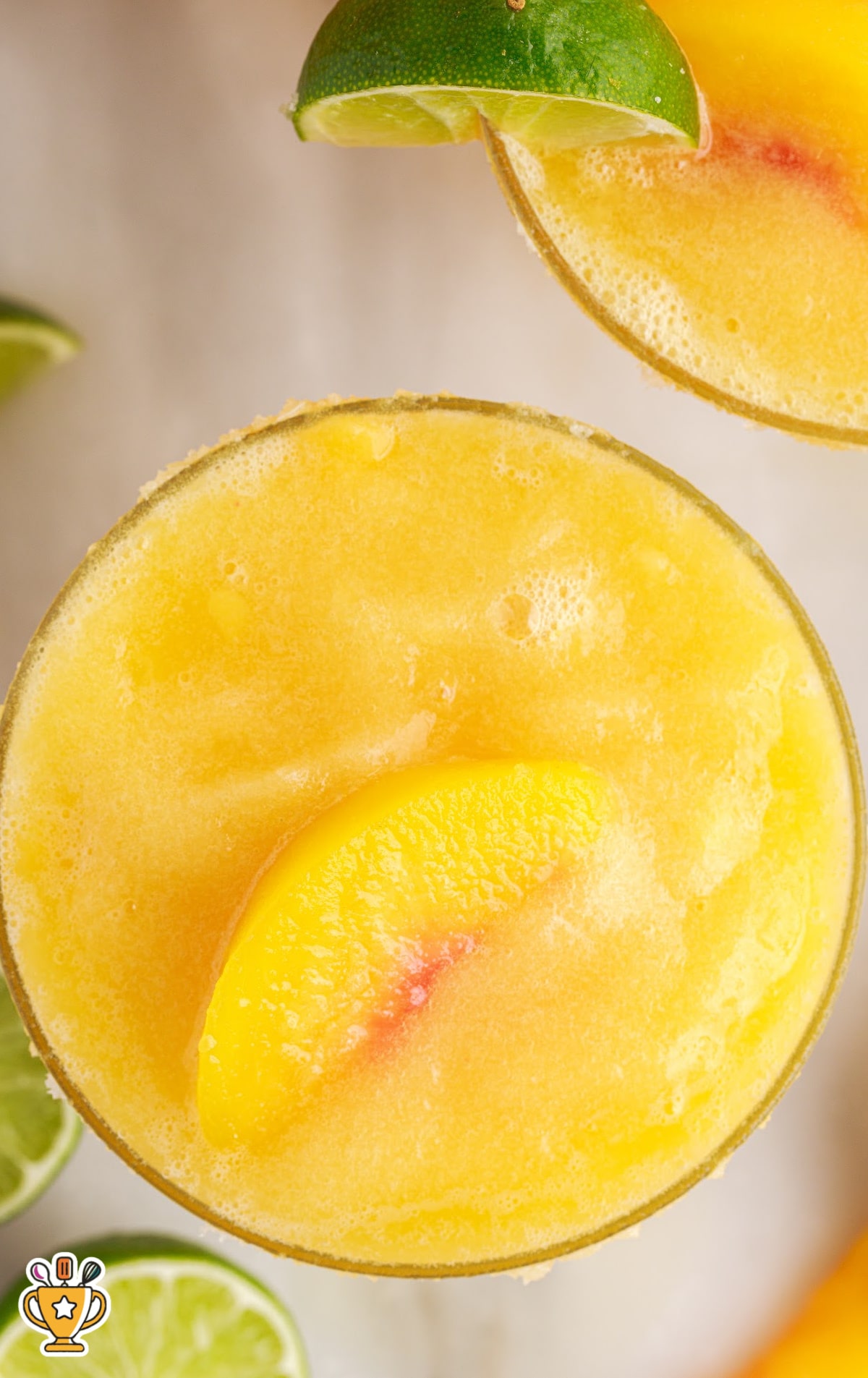 a top down photo of peach margarita garnished with a lime slice and served over ice in a cocktail glass
