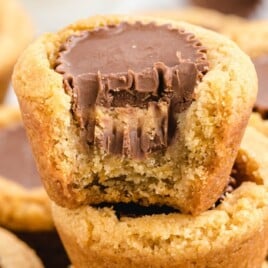 Golden peanut butter cookie cups arranged on parchment paper with chocolate centers, ready to enjoy as a sweet treat.