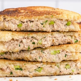 Close-up of a golden-brown tuna melt sandwich with melted cheese, flaky tuna filling, and crispy toasted bread