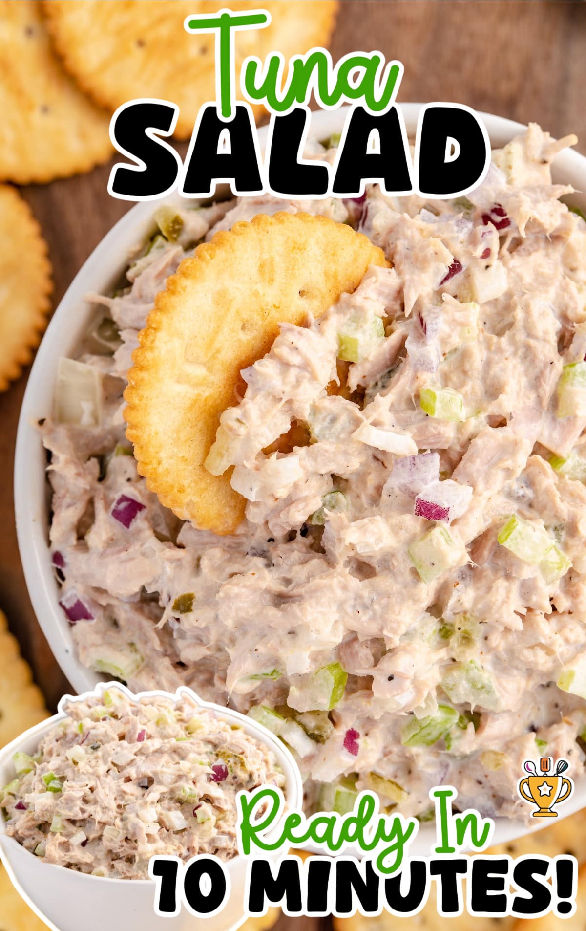 Overhead view of tuna salad with a cracker dipped in, placed on a rustic wooden surface and surrounded by more crackers.