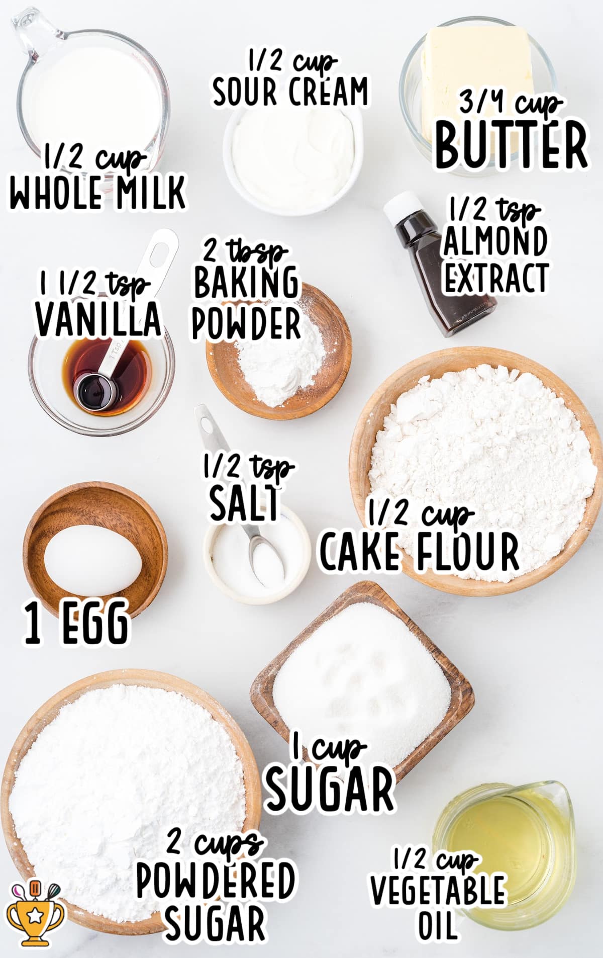 Overhead view of ingredients for vanilla snack cake, including flour, eggs, sugar, butter, and vanilla extract.