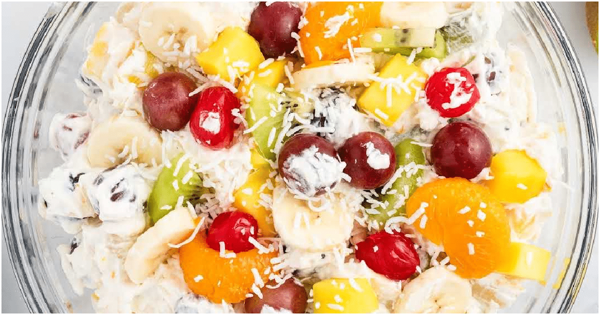 Tropical cheesecake fruit salad with pineapple, mango, kiwi, and creamy cheesecake filling in a glass bowl
