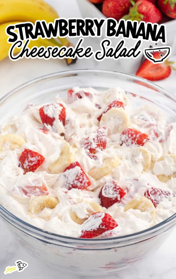 Strawberry banana cheesecake salad with Cool Whip and creamy filling in a white bowl, garnished with fresh sliced fruit