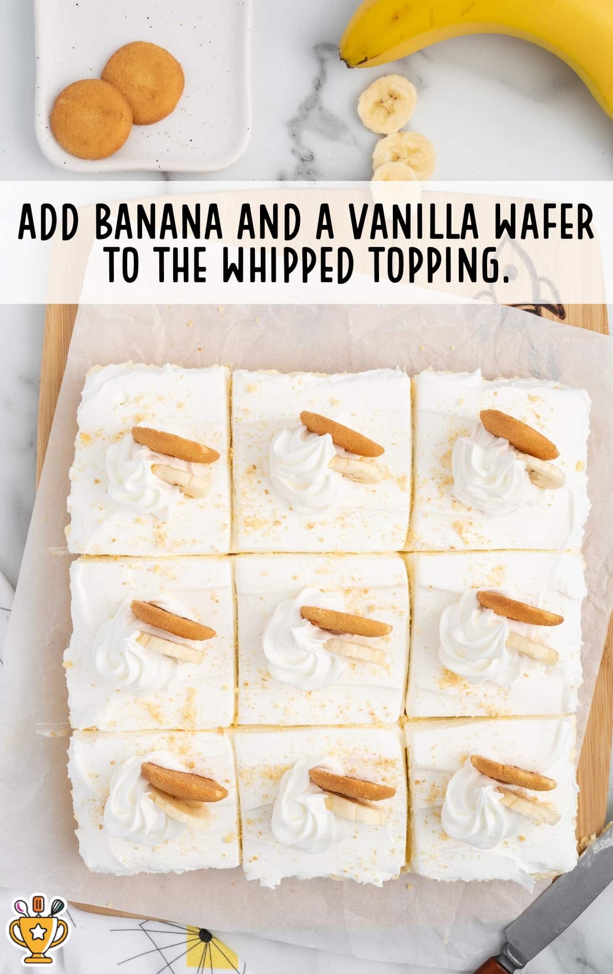 Overhead photo of banana cheesecake bars cut into squares, each topped with whipped cream, banana slices, and a Nilla wafer, with text instructions.