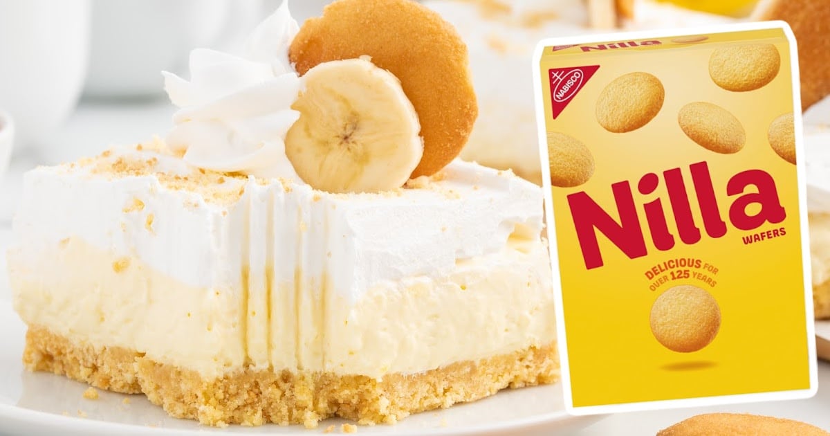 Banana cheesecake bar slice topped with whipped cream, banana slice, and Nilla wafer, with a Nilla Wafers box to the side.