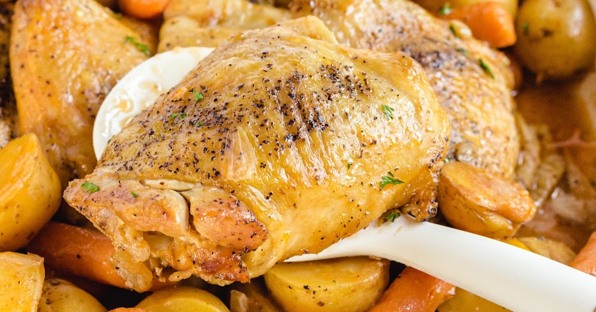 Hearty serving of slow cooker chicken thigh, carrots, and potatoes on a white plate next to the serving dish.