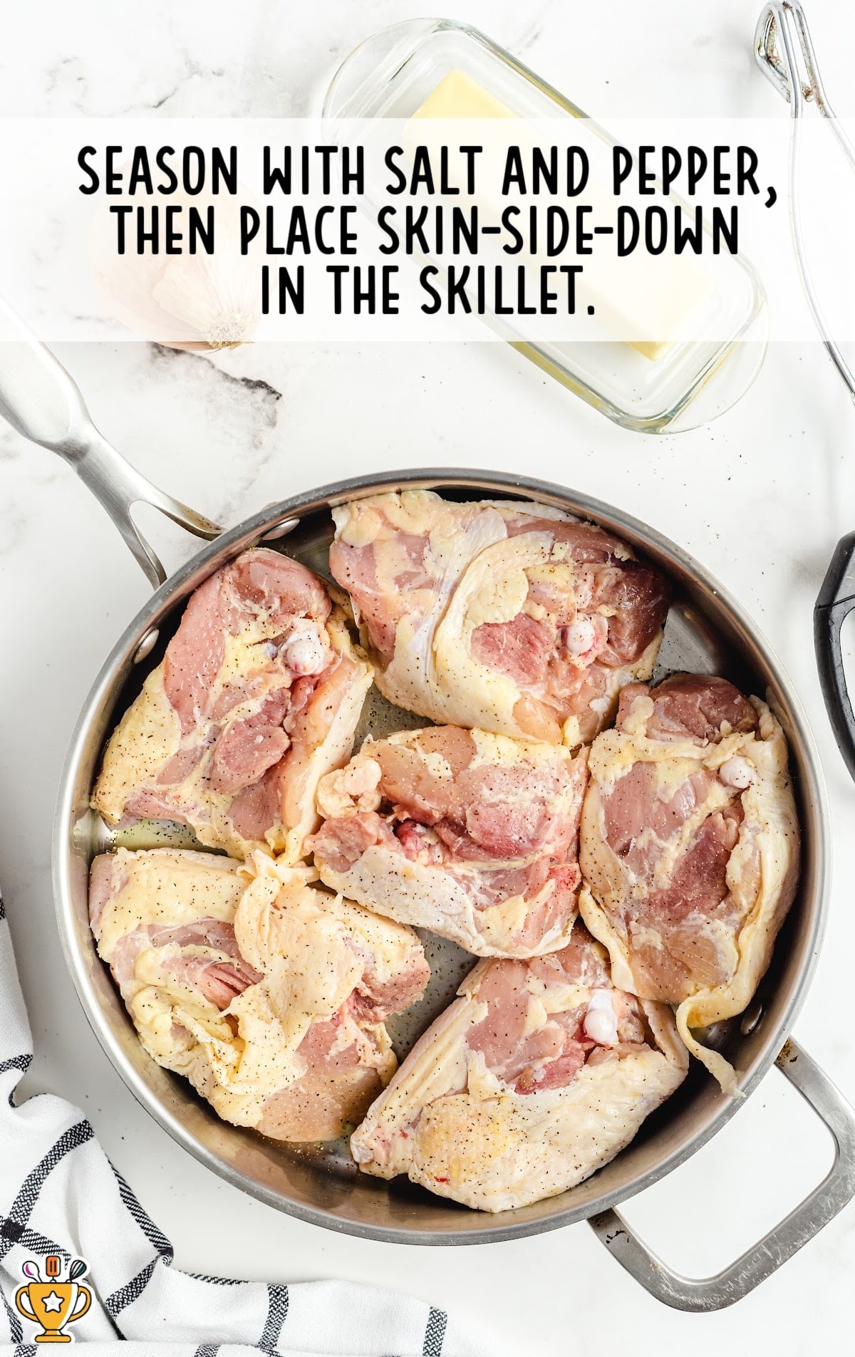 Raw seasoned chicken thighs arranged skin-side down in a stainless steel skillet, ready for searing before slow cooking.