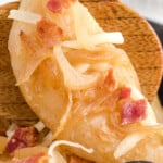Close-up of a crispy fried pierogi topped with sautéed onions, bacon, and melted cheese on a wooden spoon, with a bold text overlay that reads "The Best Fried Pierogies" and "Stuffed with Cheesy Potato Goodness!" along with a small bowl of pierogies and the Best Blog Recipes logo. Ask ChatGPT