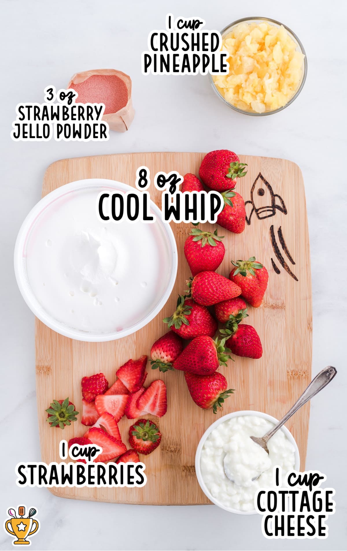 Image showing all the ingredients needed to make strawberry Jello salad, including fresh strawberries, Cool Whip, crushed pineapple, cottage cheese, and strawberry Jello powder on a wooden cutting board.