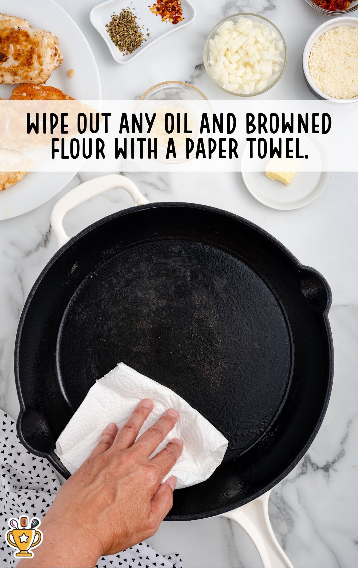 Hand wiping out excess oil and flour from a skillet with a paper towel before making the sauce.