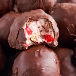 A large bowl filled with chocolate-covered Martha Washington candies, with one candy cut in half to show the inside filling.