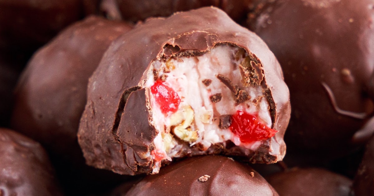 A close-up of Martha Washington candy cut open, revealing the creamy coconut, cherry, and pecan filling wrapped in chocolate.
