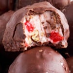 A close-up of Martha Washington candy cut in half, showing the creamy cherry and pecan filling inside a chocolate coating.
