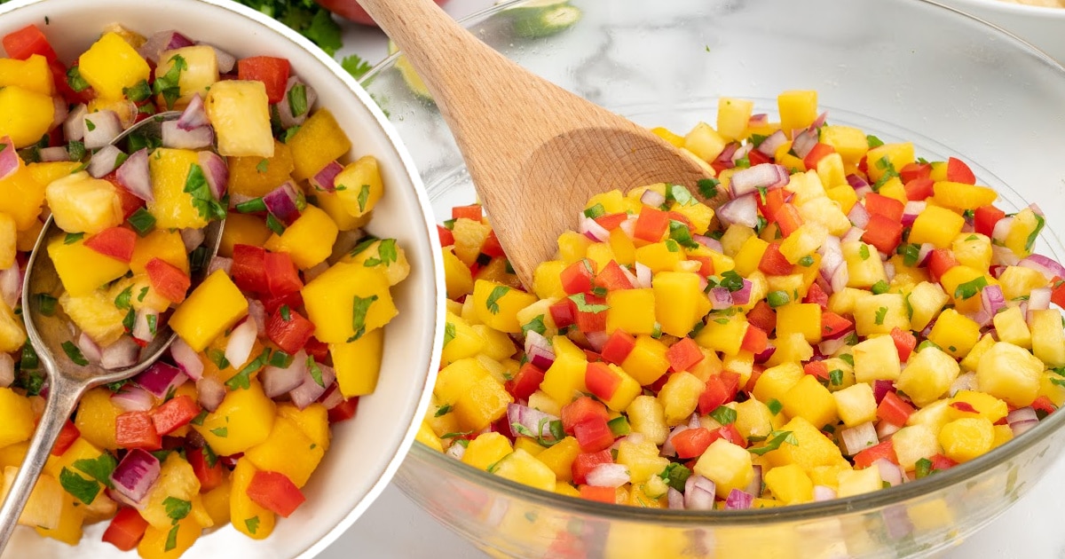 Two side-by-side bowls of freshly made pineapple mango salsa, one being mixed with a wooden spoon and the other with a serving spoon.