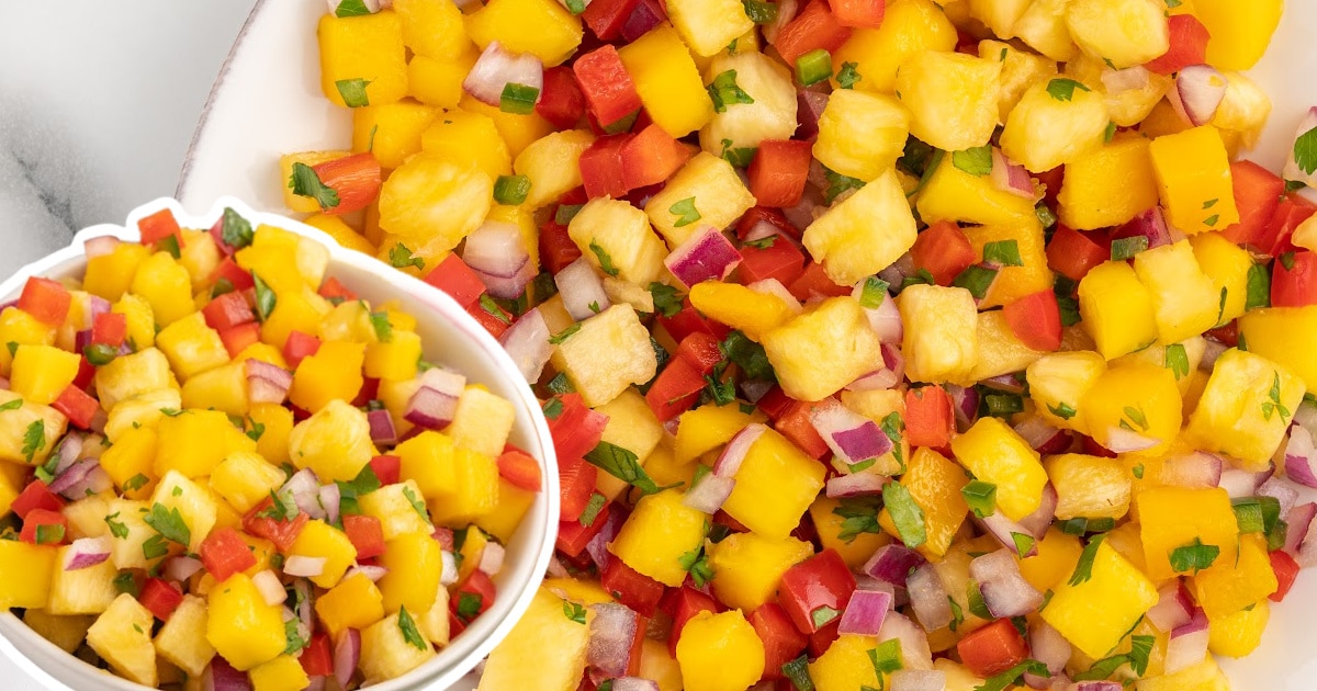 Zoomed-in view of pineapple mango salsa in two bowls with diced mango, pineapple, red pepper, onion, and chopped cilantro.