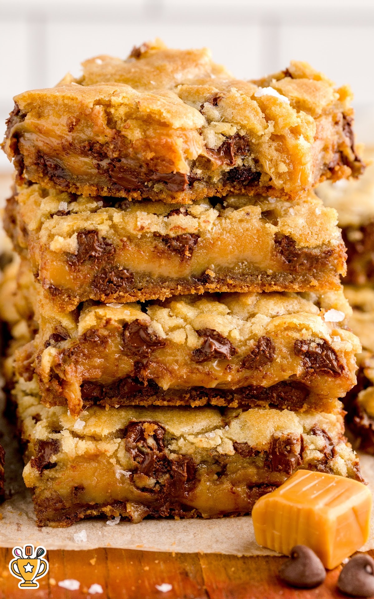 A tall stack of salted caramel chocolate chip cookie bars with golden edges, gooey caramel filling, and melted chocolate throughout.