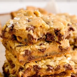 Overhead view of a pan of salted caramel chocolate chip cookie bars cut into squares, with recipe title and description text overlay.