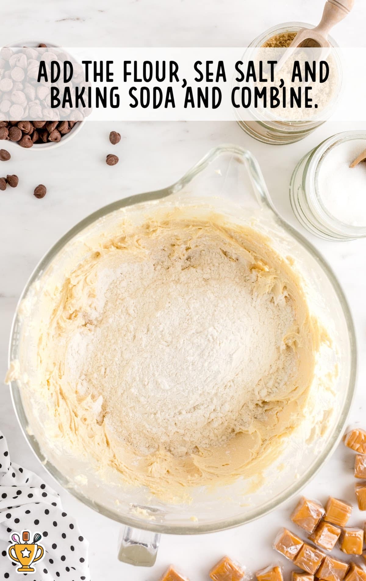 Mixing bowl filled with cookie dough base and flour, sea salt, and baking soda added on top before mixing.
