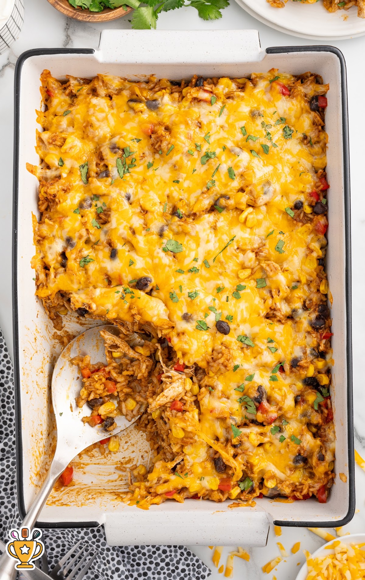 Overhead view of a baked Mexican chicken and rice casserole with melted cheese, black beans, and corn, easy family dinner casserole.