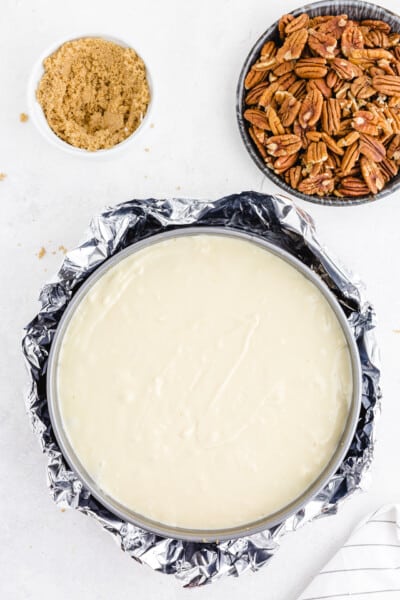 Wrap the bottom of the springform pan in 1 to 2 layers of aluminum foil. Place the pan into a larger pan and pour water into the larger pan until it comes up about 1 inch around all sides of the springform pan, forming a water bath for the cheesecake.