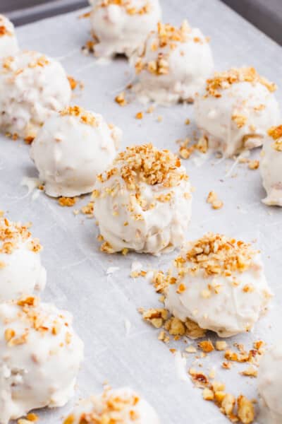 Butter Pecan Cheesecake Bite coated in White Almond Bark and Topped with Chopped Pecans