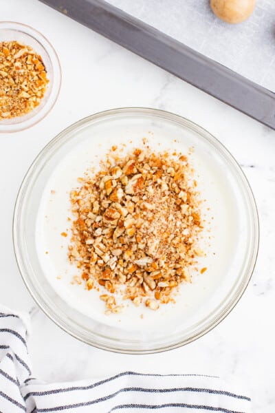 Melted White Almond Bark in a White Bowl with 2 TBSP Finely Chopped Pecans