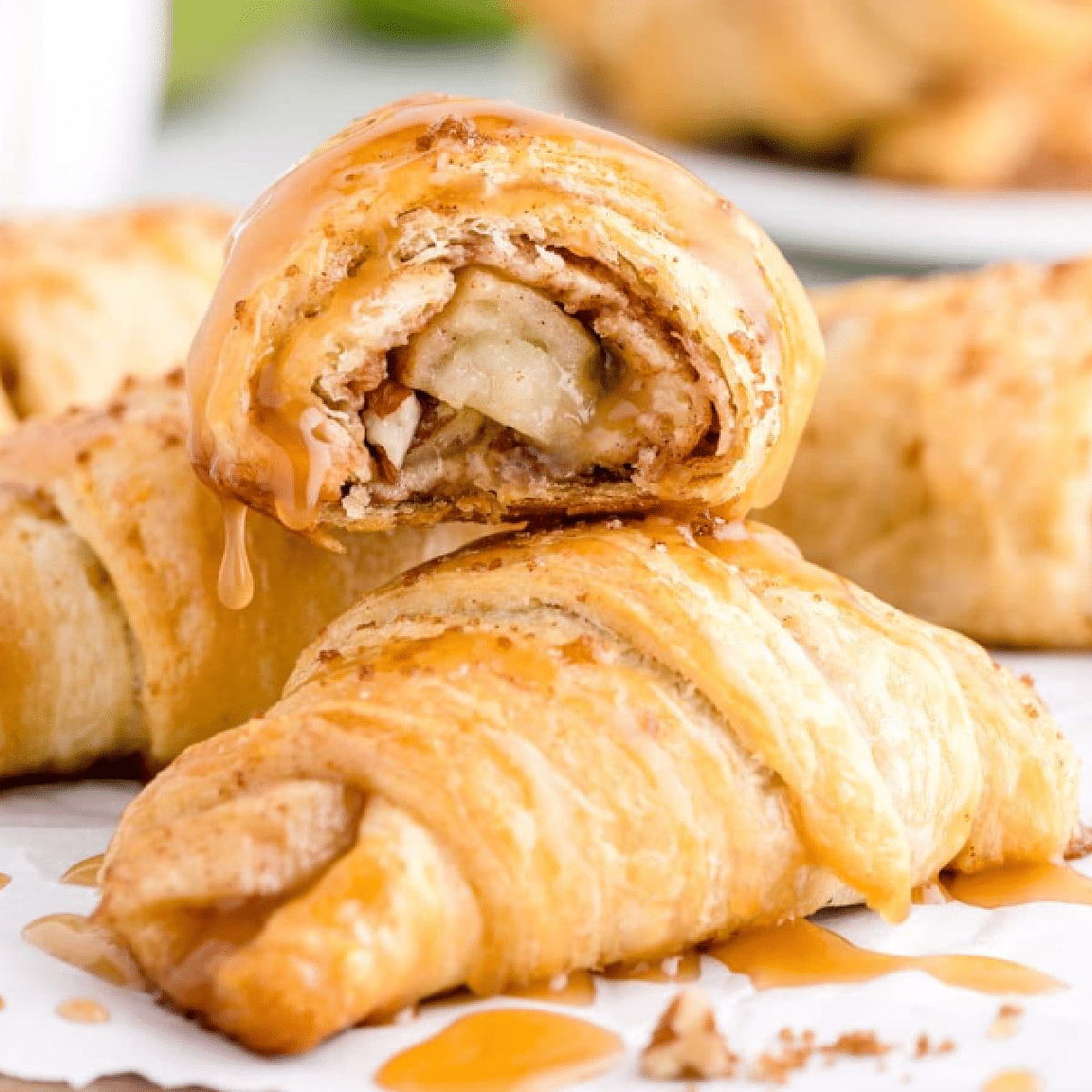 Flaky crescent roll apple pie bites filled with caramel-coated apple slices and drizzled with golden caramel sauce