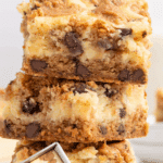 Stack of chocolate chip cheesecake bars made with layers of cookie dough and creamy cheesecake.