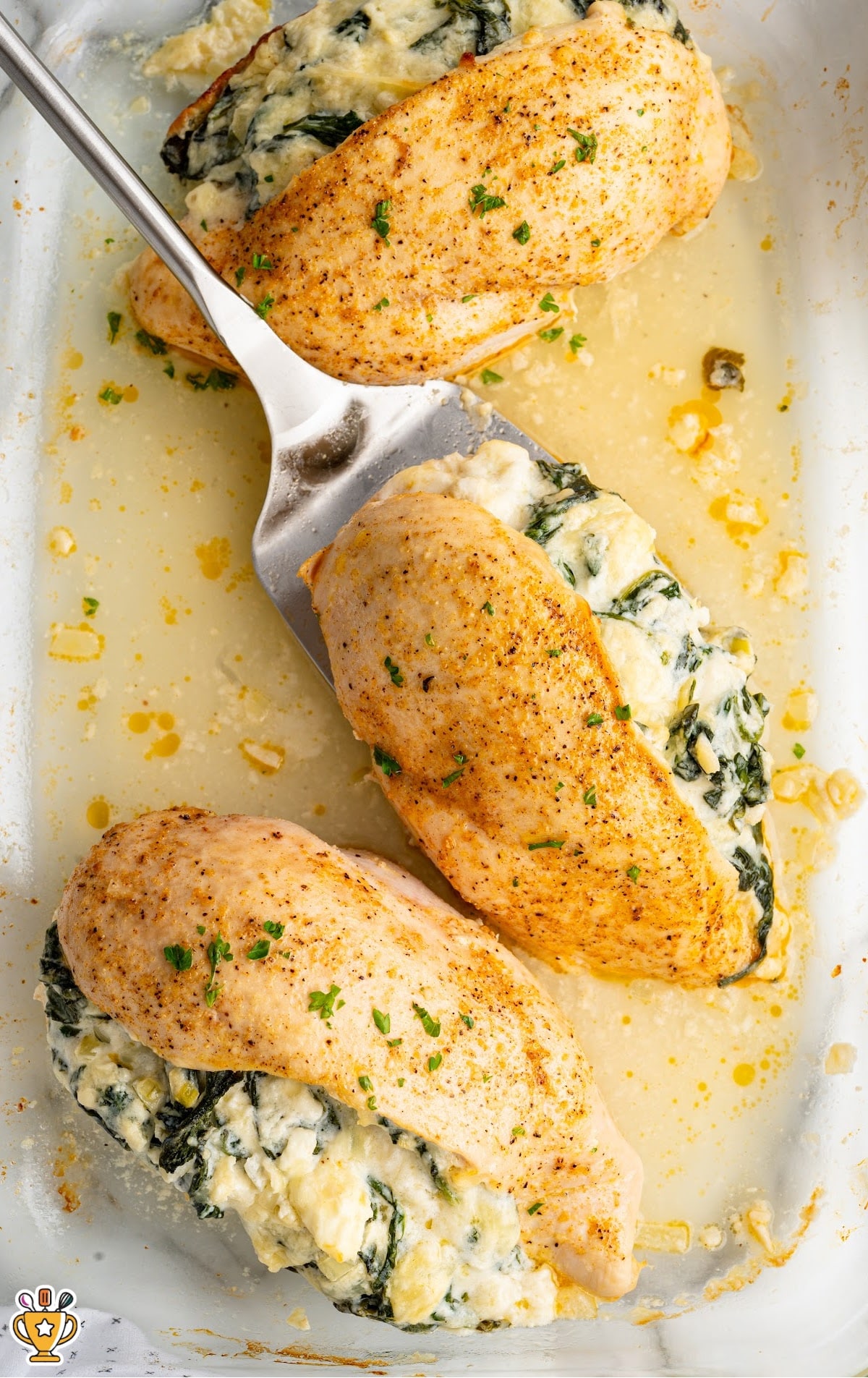 Baked spinach stuffed chicken breasts in a baking dish, showing tender chicken packed with a creamy spinach and cheese mixture.