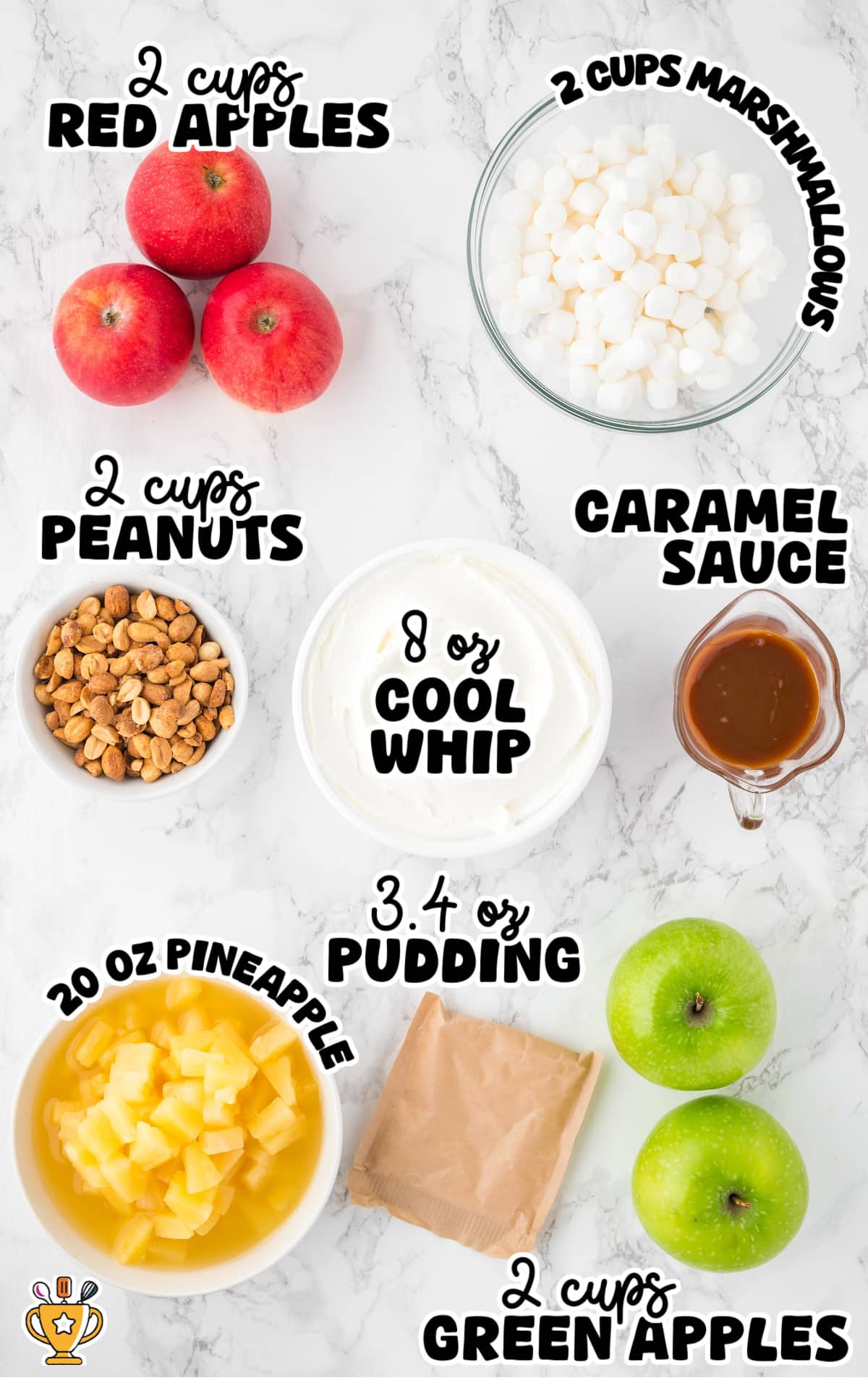 Overhead view of labeled ingredients for Taffy Apple Salad, including red apples, green apples, mini marshmallows, peanuts, pineapple chunks, Cool Whip, caramel sauce, and a packet of vanilla pudding mix, all arranged on a white marble surface.