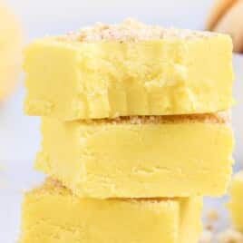 Stacked banana fudge squares showing a thick, creamy texture with crushed vanilla wafer crumbs layered between and sprinkled on top.