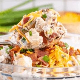 Loaded baked potato salad with bacon, cheddar cheese, and green onions in a creamy dressing.