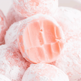 Soft strawberry truffles coated in powdered sugar with a creamy pink center.